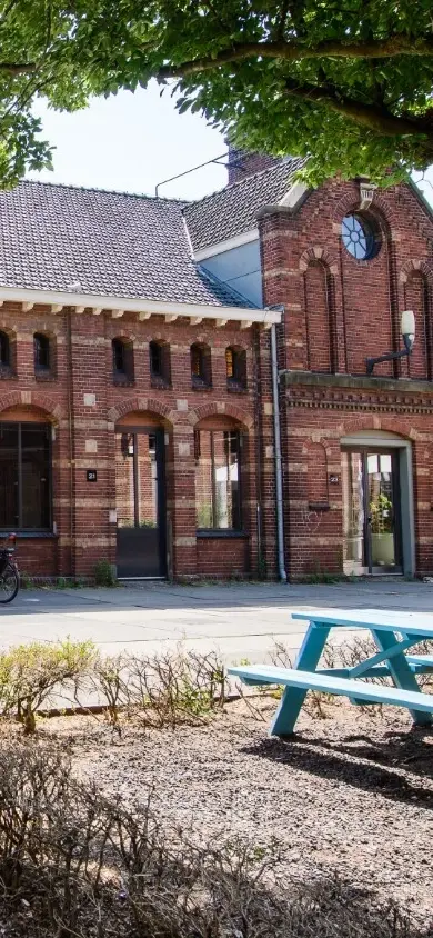 Exterior view of a red brick building at Westergasfabriek in Amsterdam, with large glass windows and traditional architecture
